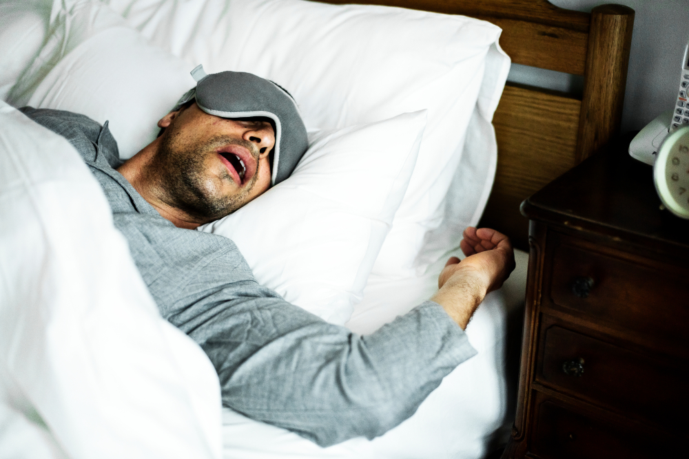 Man with eye mask snores while sleeping.